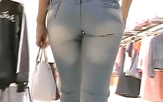 Two girls in the tight blue jeans are strolling over the shops followed by camera man